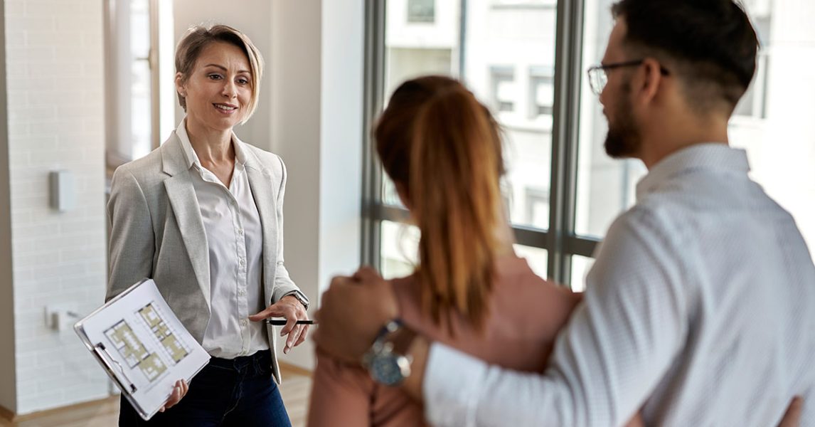 female-real-estate-agent-communicating-with-couple-while-showing-them-new-apartment