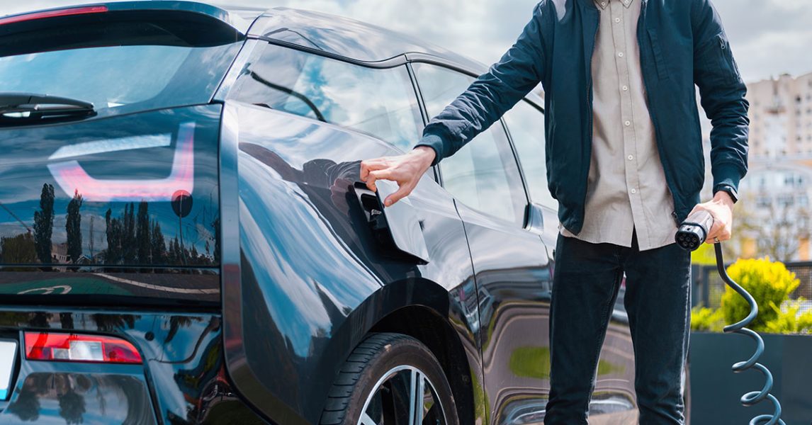 man-closing-cars-charge-socket-holding-charger-charge-station