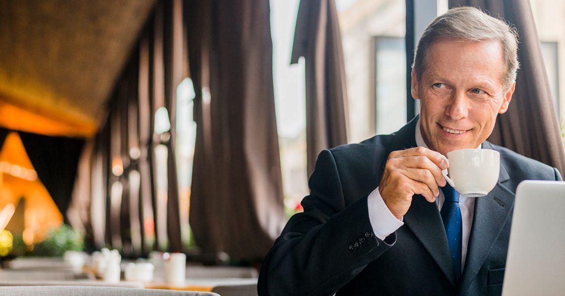 happy-businessman-drinking-coffee-with-laptop-desk