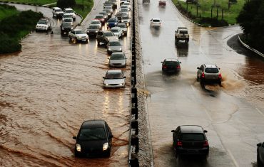 Motorists drive through water on a flooding highway